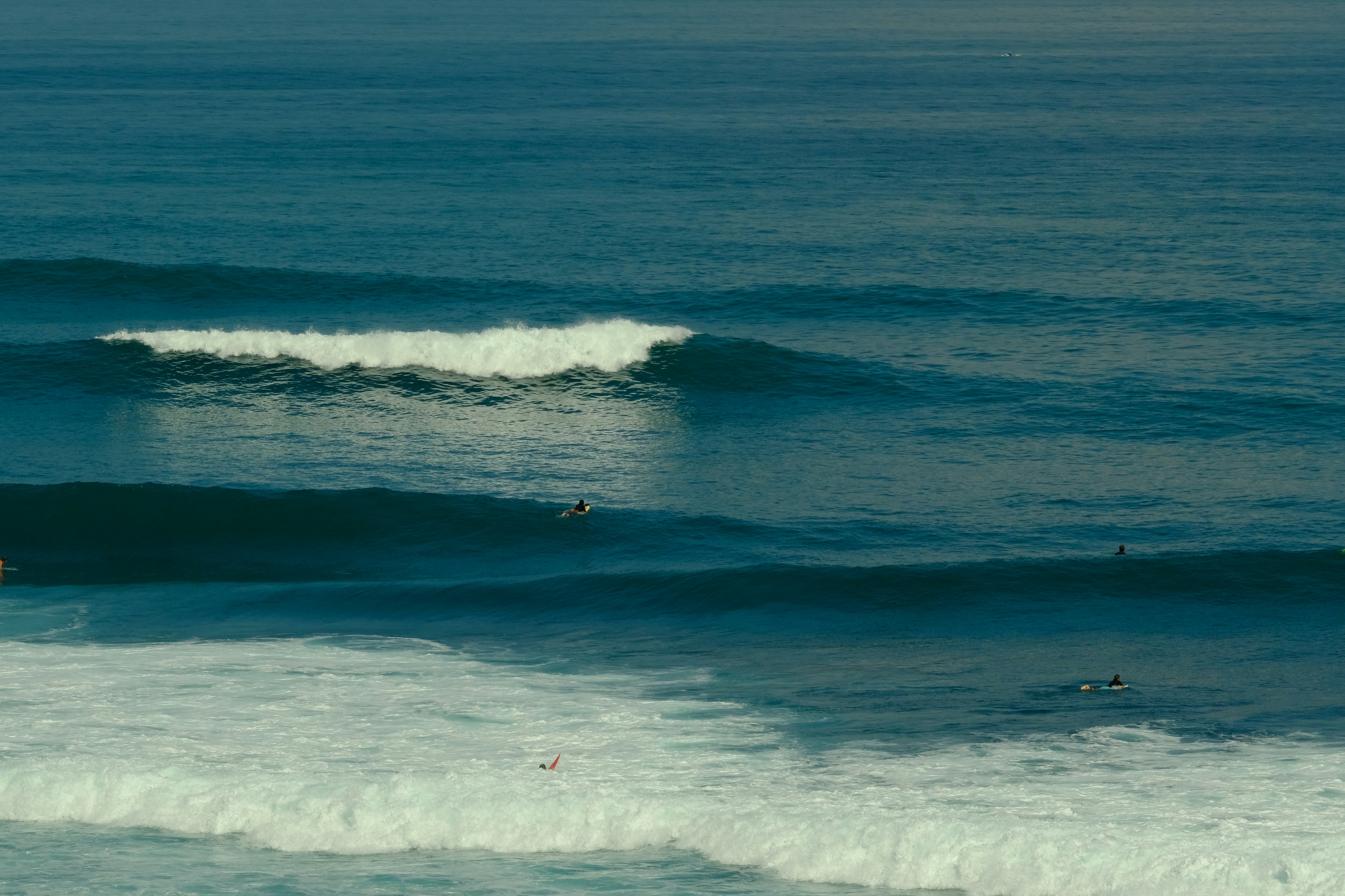 Surfer im Wasser vor den Klippen von Uluwatu, Bali